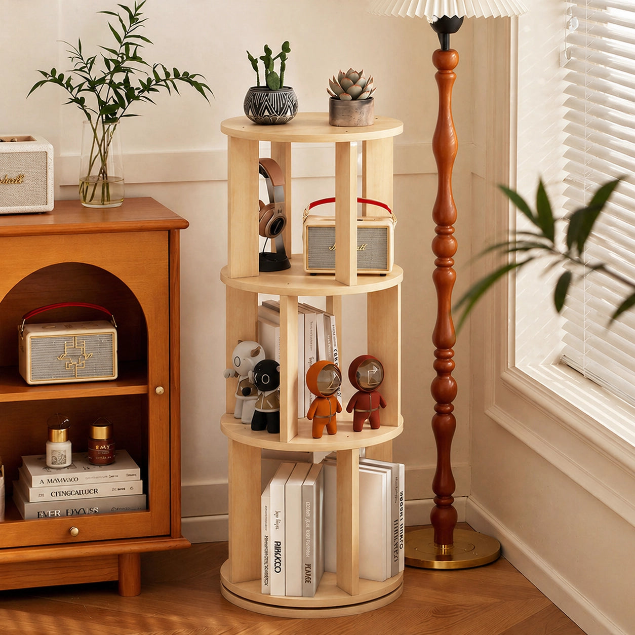 Three-tier round rotating kids bookshelf holding toys and small audio speakers next to a lamp