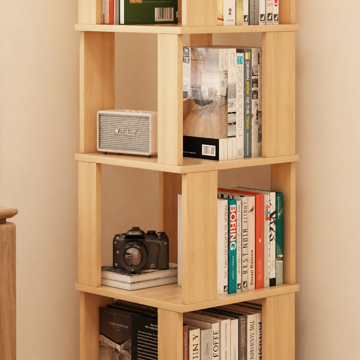 Close-up of shelves on a solid pine rotating bookshelf holding books, a speaker, and a camera
