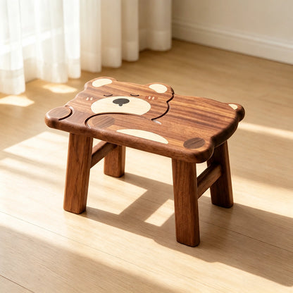 Angled view of a sleeping bear toddler stool in solid ebony wood on a light wooden floor