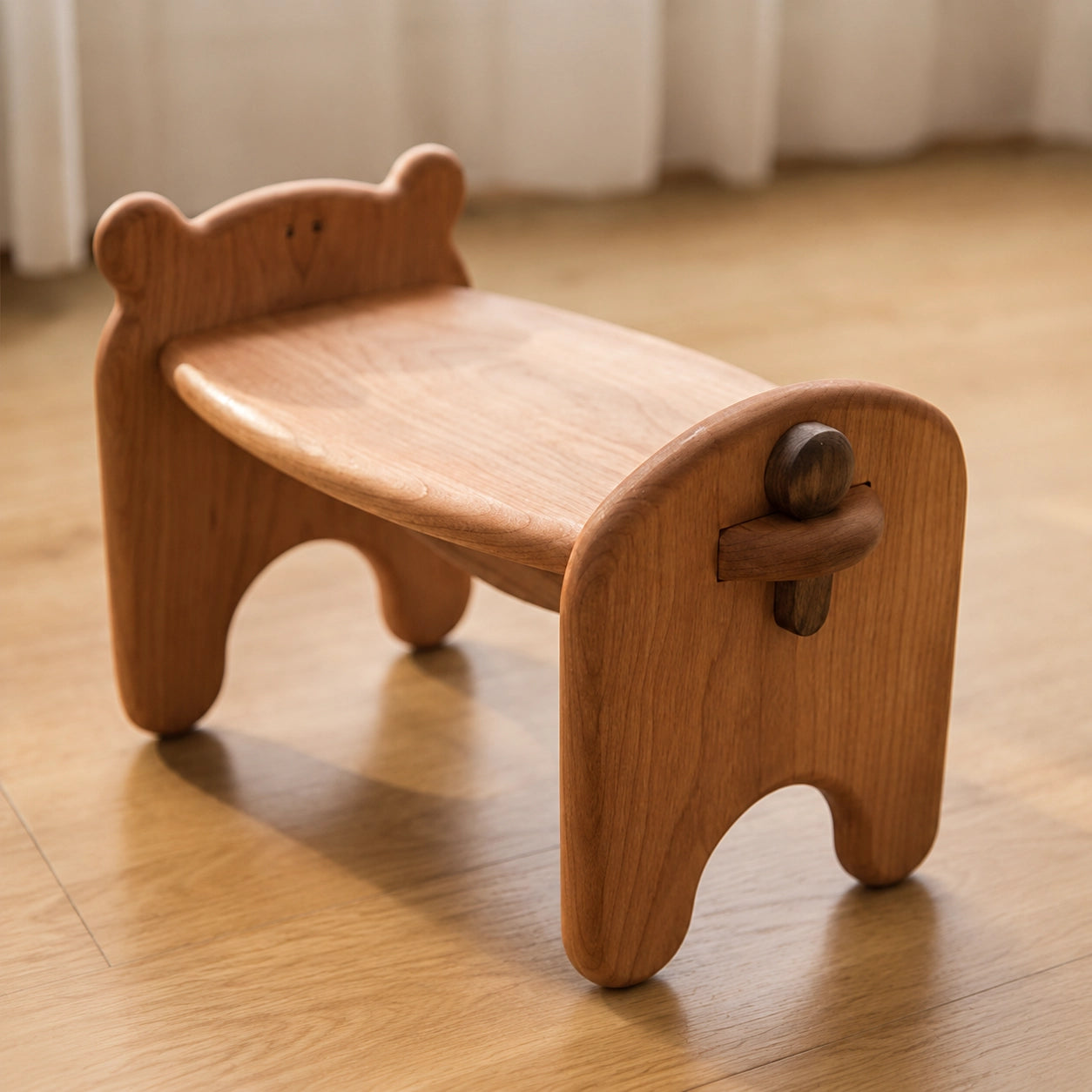 Three-quarter view of the assembled solid cherry wood toddler bear stool on a wooden floor