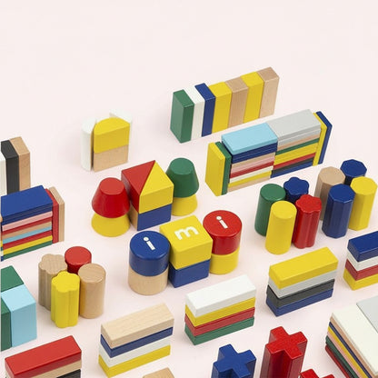 Overhead view of various colorful solid beech wood blocks in geometric shapes scattered across a light surface