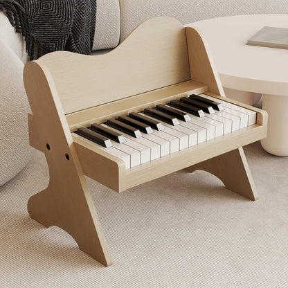 Three-quarter view of a plywood toddler electronic piano with a light natural wood finish on a rug