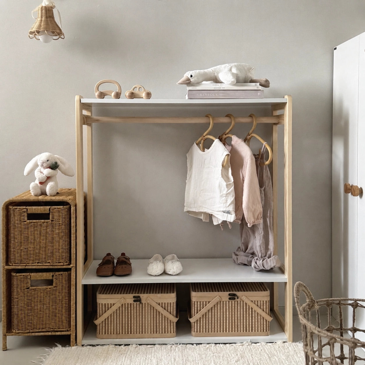 Front view of a toddler garment rack and wardrobe filled with children clothes and storage baskets