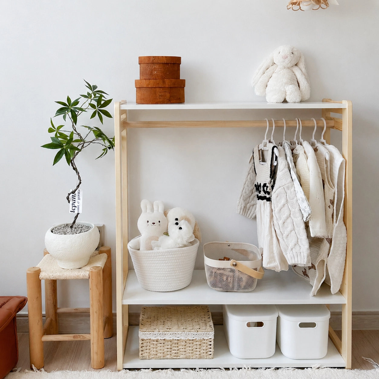 Solid pine toddler clothing rack with white storage bins on the lower shelf next to a potted plant