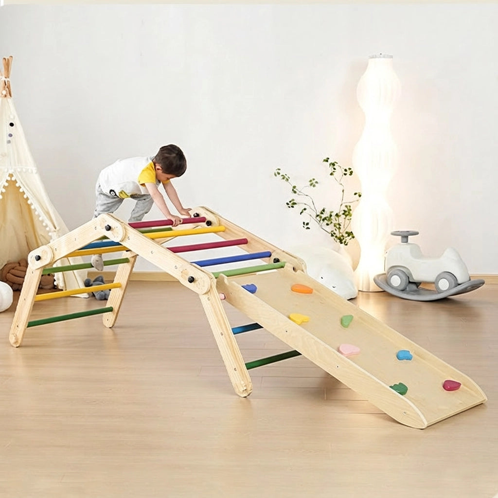 Toddler boy climbing a rainbow-rung Montessori climbing set configuration with a colorful rock ramp