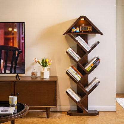 Taller tree shape floor bookshelf filled with books next to a dark wood TV console table