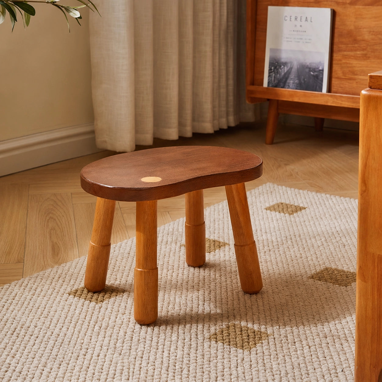 Angled view of a single two-tone bean-shaped low stool on a textured rug in a room