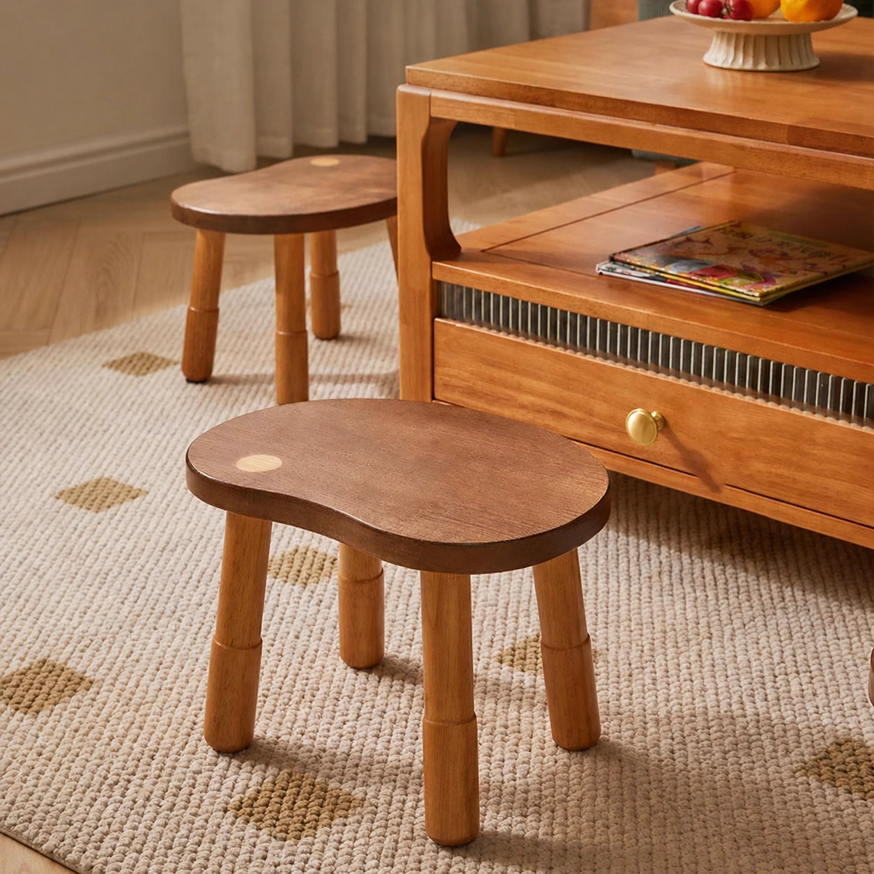 Two-tone bean-shaped low stools made of solid rubber wood placed on a rug next to a coffee table