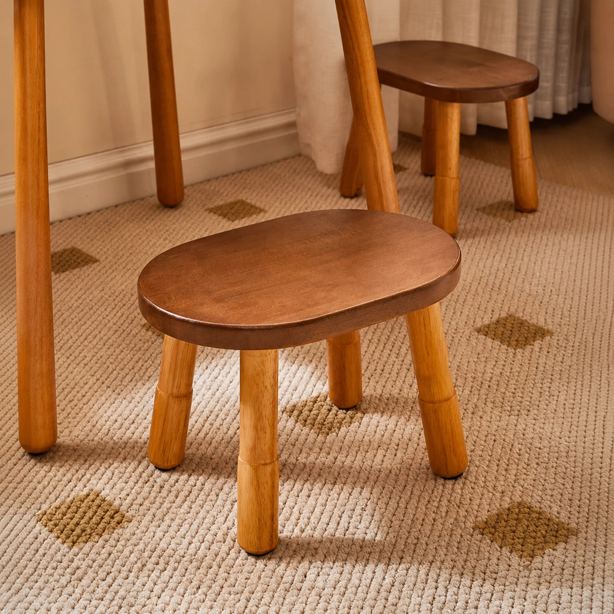 Solid rubber wood low stool positioned under a wooden table on a textured area rug