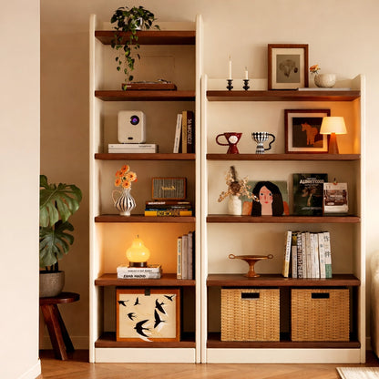Close-up view of two-tone solid wood bookshelves decorated with books, a projector, and woven baskets